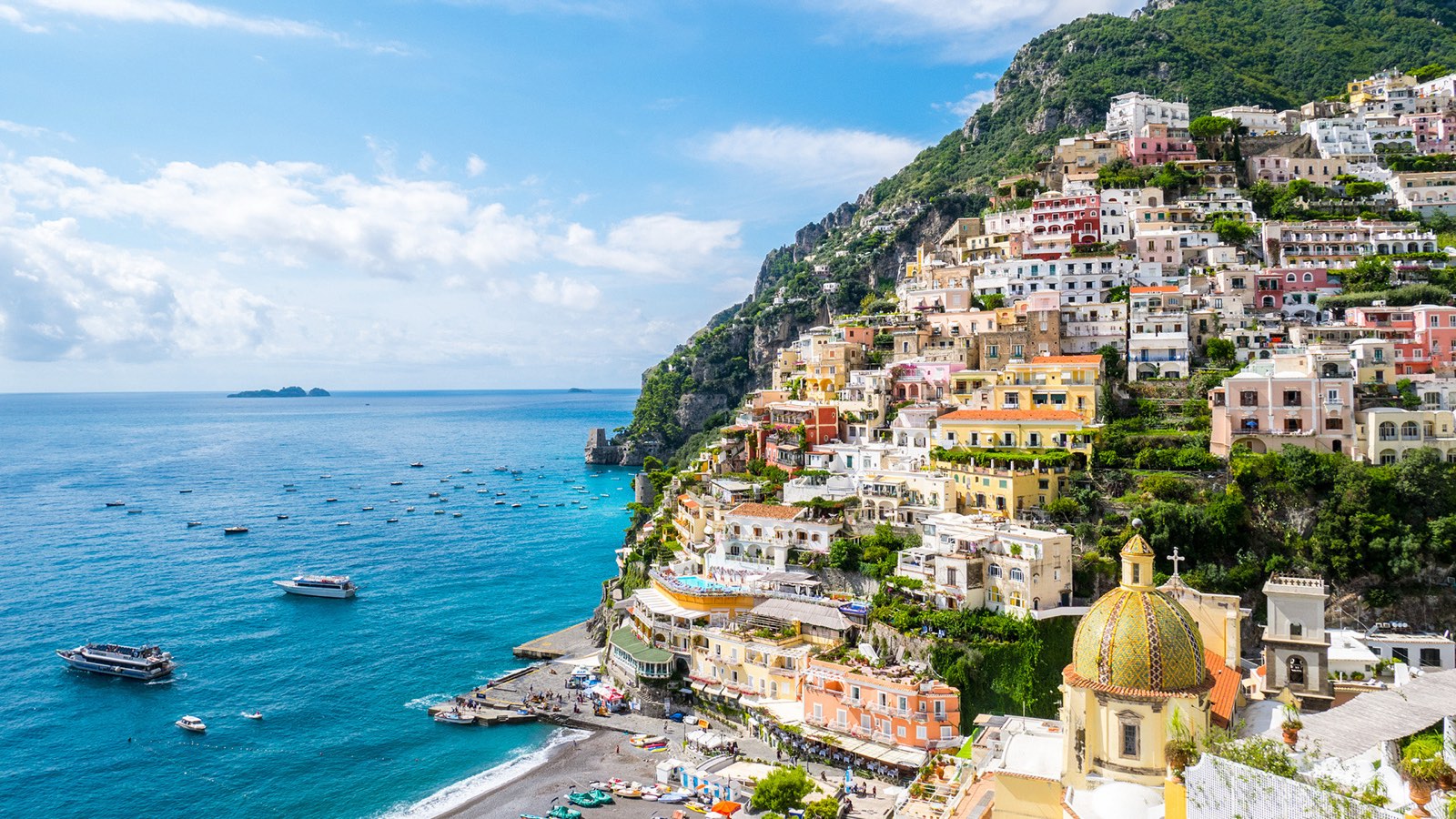 Positano's pastel houses and majolica dome climbing the hill above the Tyrrhenian Sea
